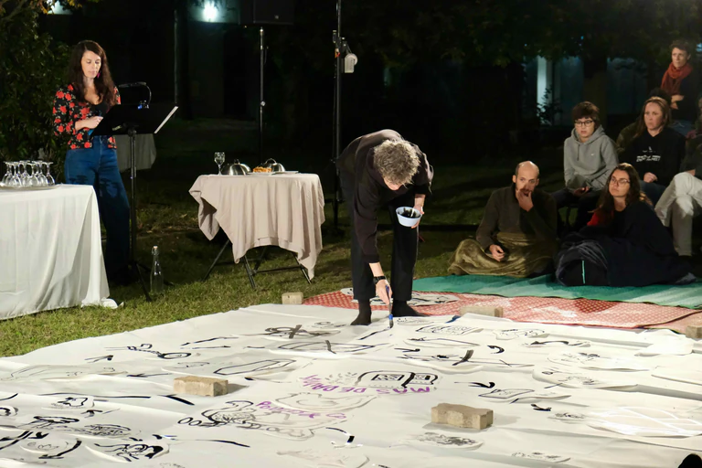 une femme lit a un pupitre et un artiste dessine aux pinceaux 