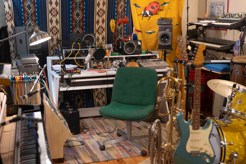 Vue d'ensemble du studio d'enregistrement de Voyou à Pantin, encombré d'instruments, de guitares, d'un clavier, de tapis à motifs et de matériel audio
