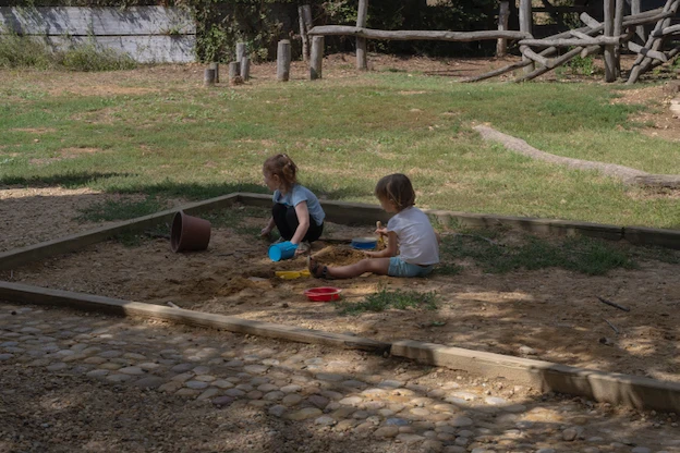 Deux enfants assis au sol avec outils de jardinage à la main