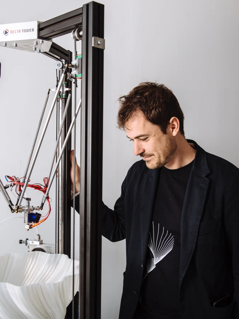 L’architecte Arthur Mamou-Mani pose aux côtés d’un tabouret qu’il a conçu et imprimé en 3D. 