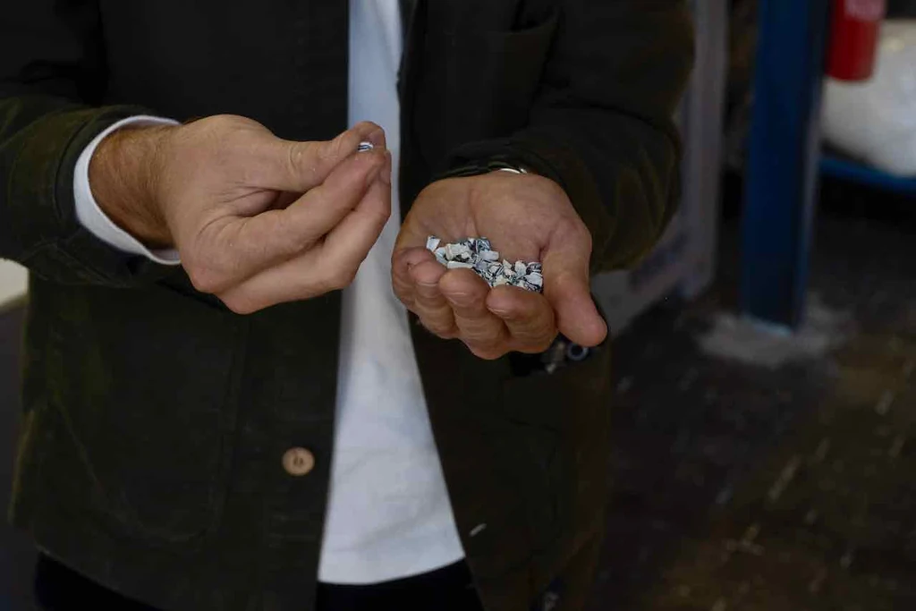 Gros plan sur les mains d'un homme tenant des granulés de plastique recyclé noir et blanc.