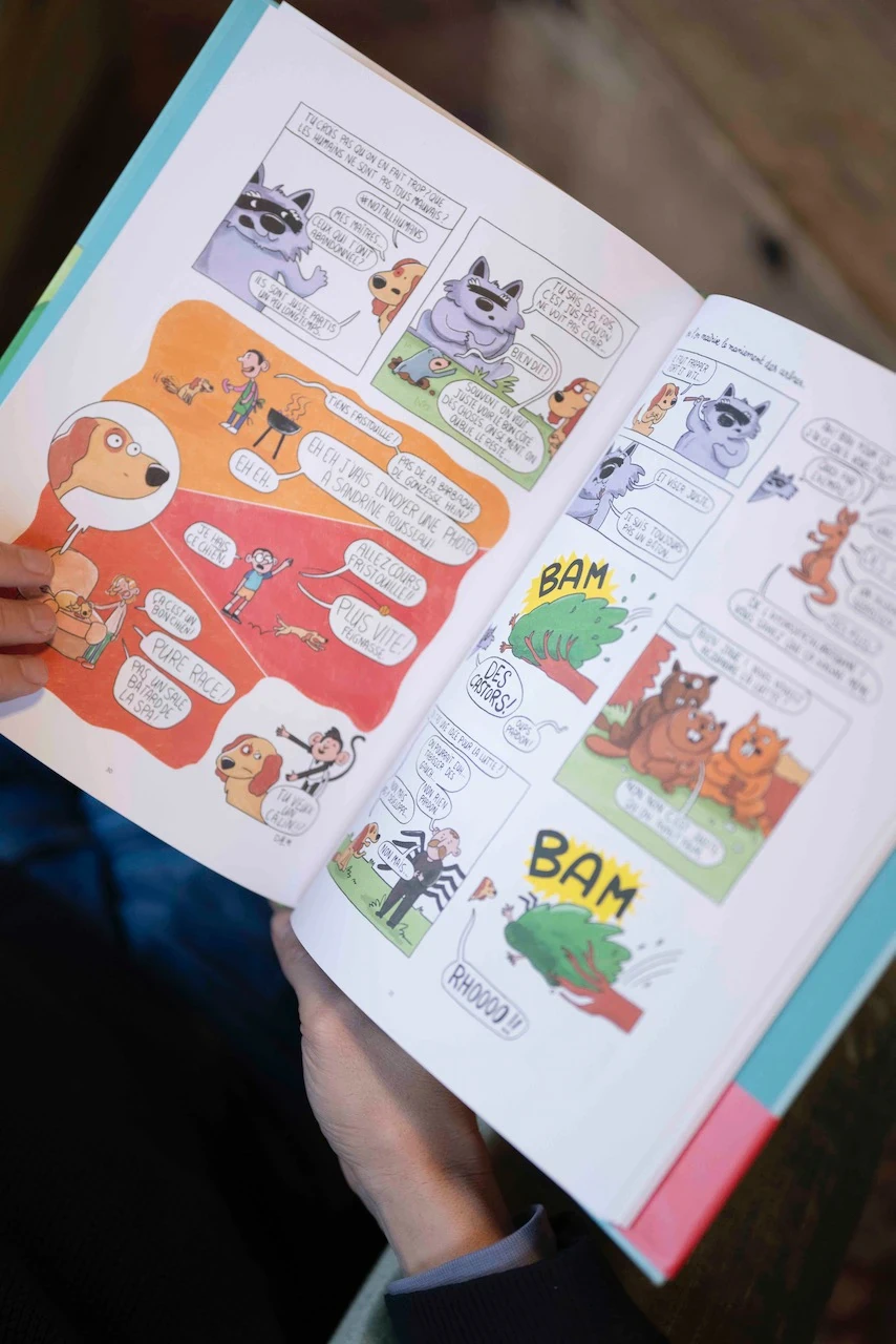 Des mains feuillettent les pages illustrées de la bande dessinée  La révolte sans précédent