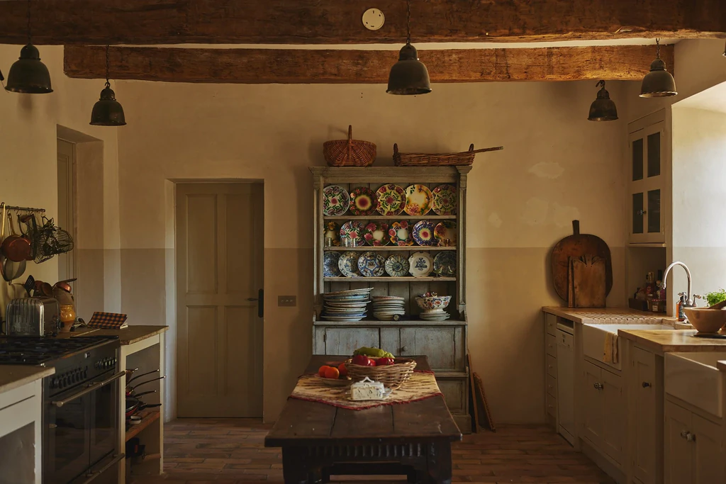 Cuisine rustique avec sol en tomettes rouge fondé et large table en bois disposée en son centre