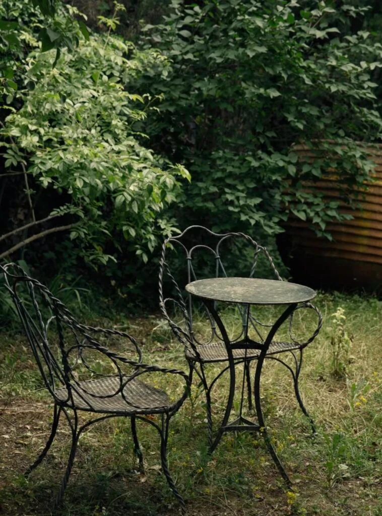 Table et deux chaises en fer forgé disposées dans un jardin