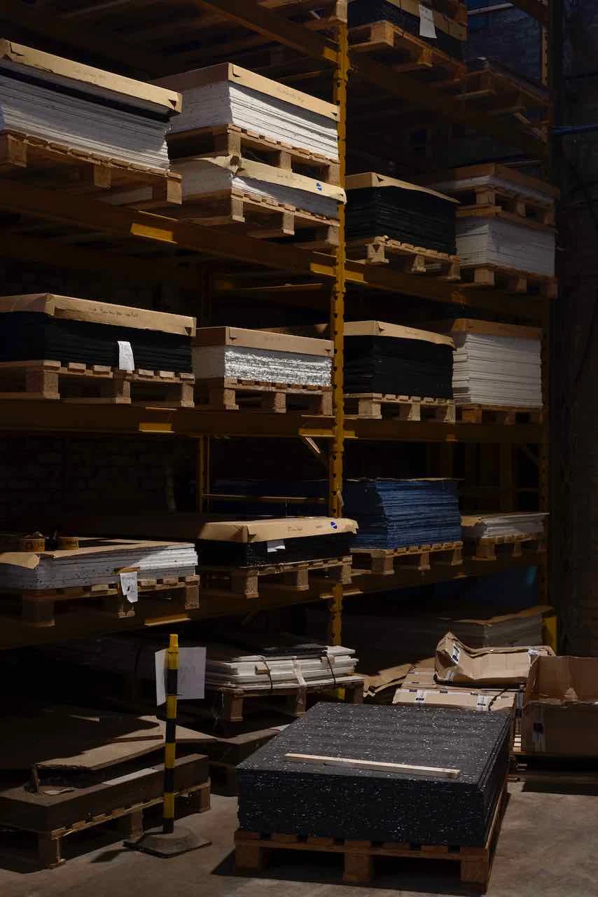 Étagères industrielles chargées de palettes de panneaux noirs, blancs et bleus en plastique recyclé.