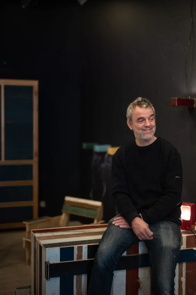 Le designer Piet Hein Eek assi sur une table de sa fabrication