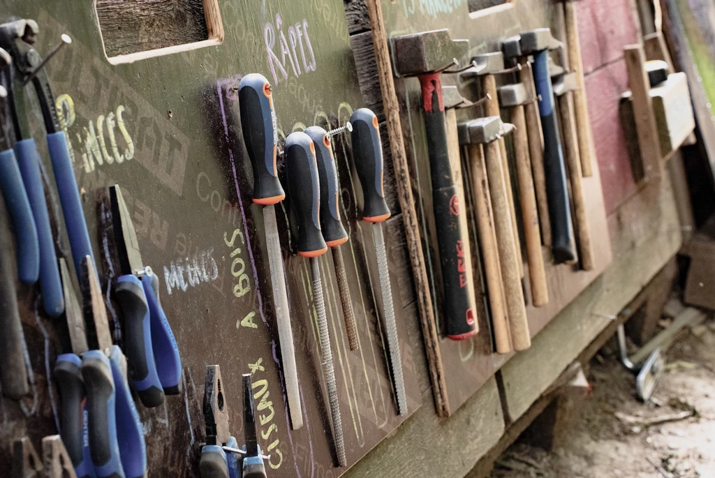 Des tournevis, pinces et marteaux rangés sur un panneau porte outils