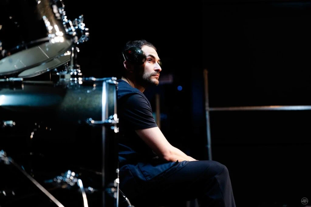 Samuel Valensi, comédien, est assis sur scène à côté d'une batterie