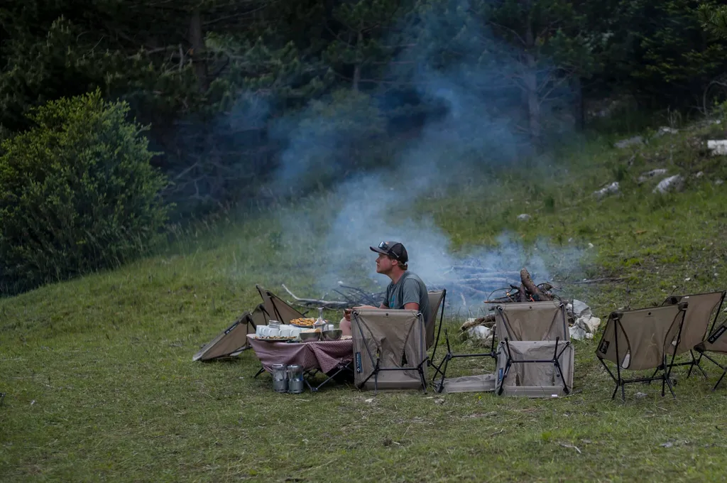 Un randonneur assis à côté d'un feu de camp regarde au loin
